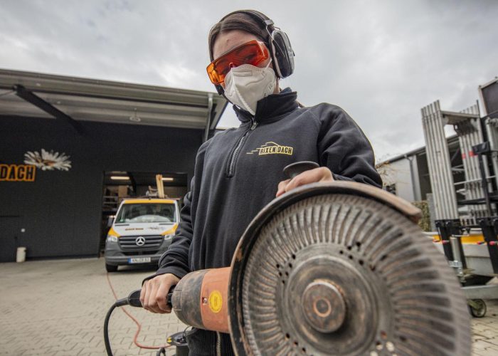 Auszubildender bei Rixen Dach schneidet präzise Materialien zu.
