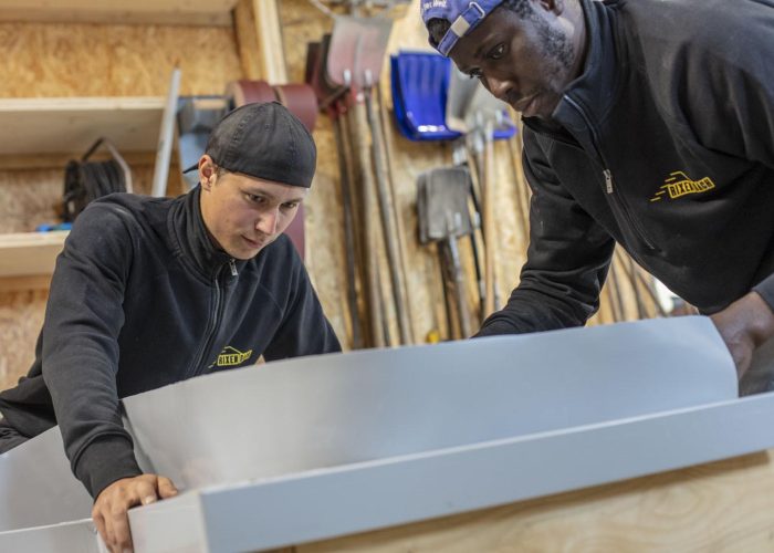 Team bei Rixen Dach führt gemeinsam präzise Blecharbeiten aus.